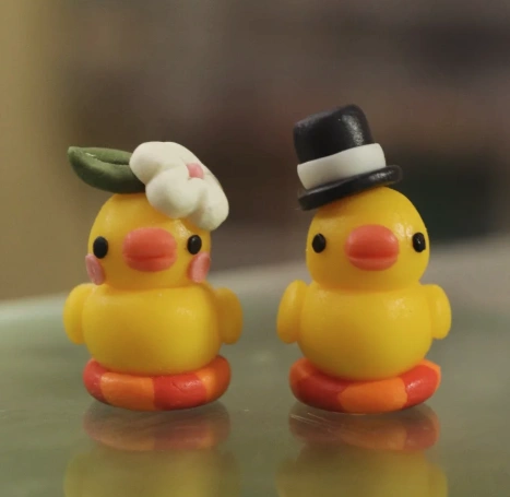 Two cheerful yellow duck figurines, one with a flower and the other in a top hat, showcasing playful craftsmanship.