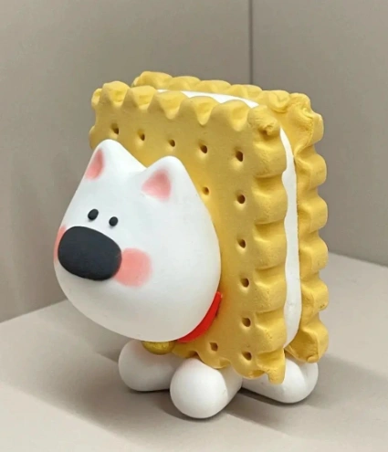 A cute clay figurine resembling a dog with a biscuit body, featuring yellow textures, a white face, and playful details.