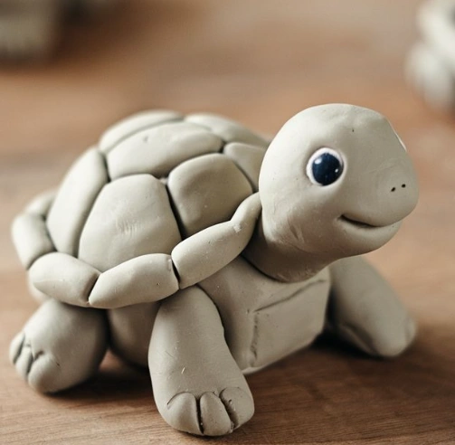 A cute clay turtle figurine with a smiling face, detailed shell, and big eyes, showcasing a soft, playful aesthetic.