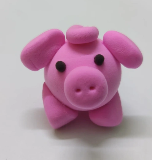 A cute pink clay pig figurine with rounded shapes, black eyes, and a curly tail, showcasing a playful and charming design.