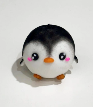 A cute clay penguin figurine featuring a round body, black and white colors, pink cheeks, and an orange beak.