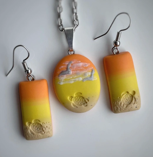 ** A vibrant clay jewelry set featuring a pendant and earrings, with orange and yellow gradients and turtle designs.